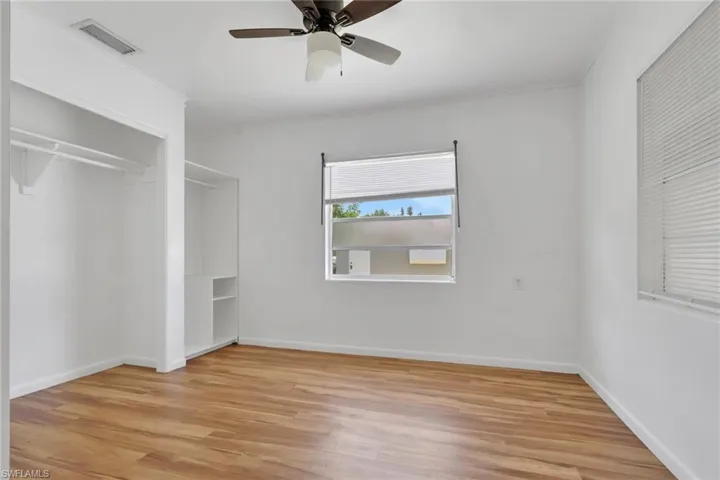 Bright room featuring wood-finish flooring, a ceiling fan with light fixture, and a window with blinds