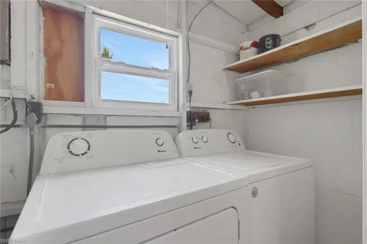 Utility area featuring a window, built-in shelving, and wood-paneled walls