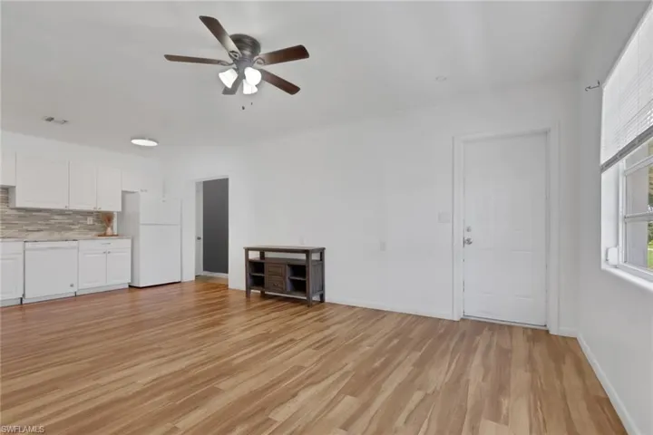 Open-concept living space featuring wood-finish flooring, white walls, and a modern ceiling fan