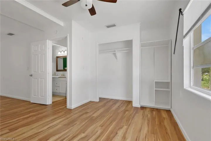 Bright room featuring wood-finish flooring, a ceiling fan, and white walls