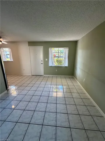 Unfurnished room with a textured ceiling, light tile patterned floors, and ceiling fan