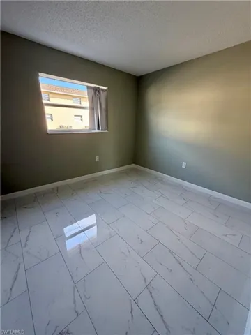 Spare room featuring light marble finish floors and a textured ceiling