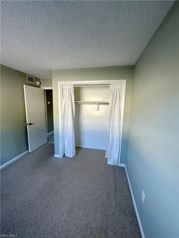 Unfurnished bedroom with carpet, a textured ceiling, and a closet