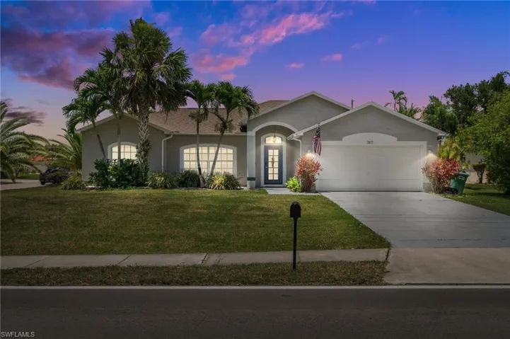 Ranch-style home with stucco siding, an attached garage, a yard, and concrete driveway
