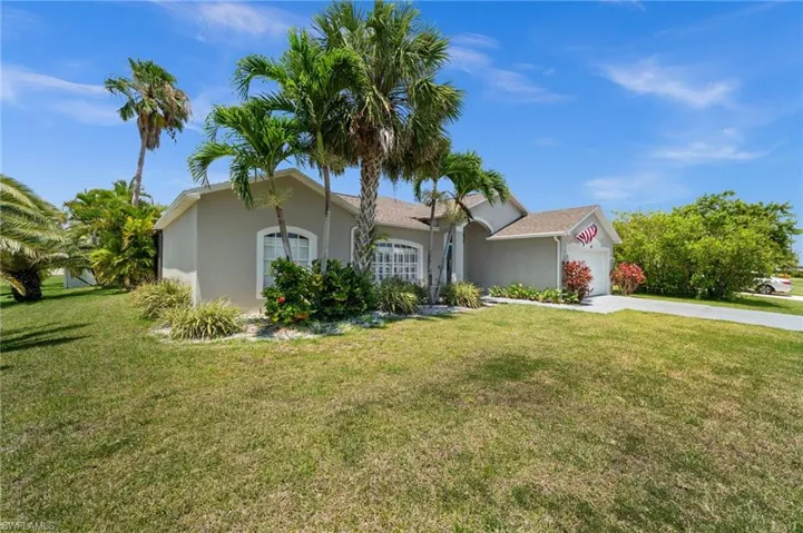 Ranch-style house with a garage, driveway, a front yard, and stucco siding