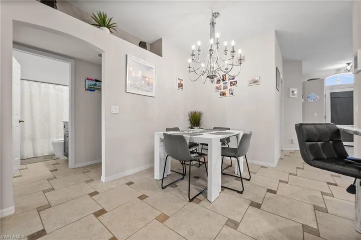 Dining room with a chandelier, baseboards, and arched walkways