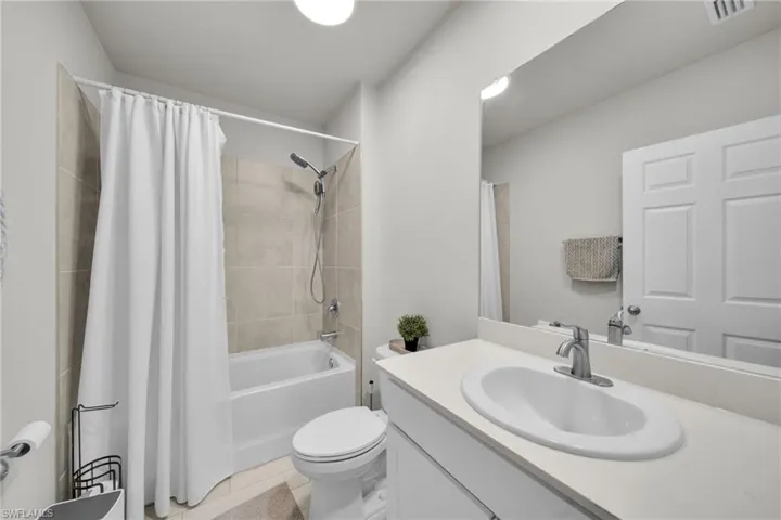 Full bath with vanity, shower / bath combo, and light tile patterned floors