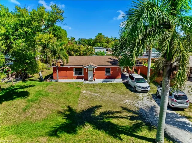 Back of property featuring a yard and dirt driveway