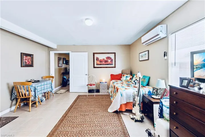 Bedroom with light tile patterned floors, baseboards, and a wall mounted air conditioner