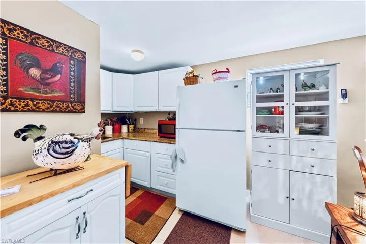 Kitchen with white cabinetry, freestanding refrigerator, and wooden counters