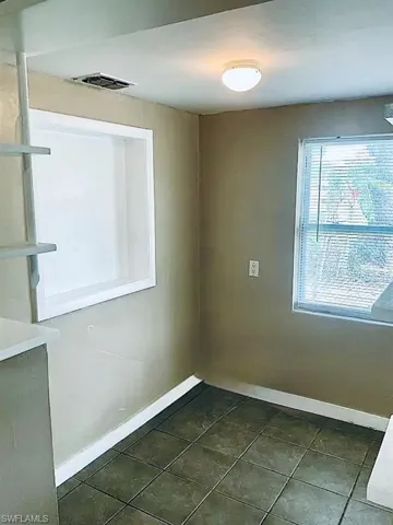 Spare room with dark tile patterned flooring, visible vents, and baseboards