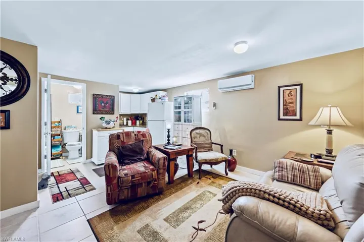 Living room with light tile patterned flooring, a wall mounted AC, and baseboards