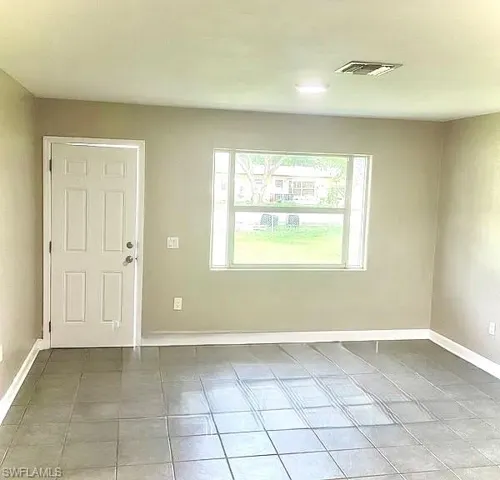 Unfurnished room featuring tile patterned floors, visible vents, and baseboards