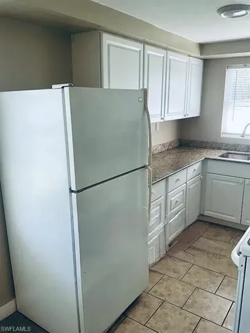 Kitchen with a sink, white appliances, and white cabinets