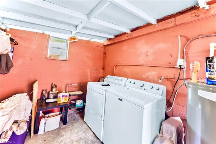 Clothes washing area featuring concrete block wall, separate washer and dryer, and laundry area