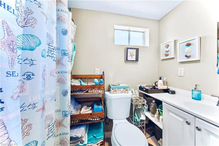 Full bathroom with curtained shower, toilet, and vanity