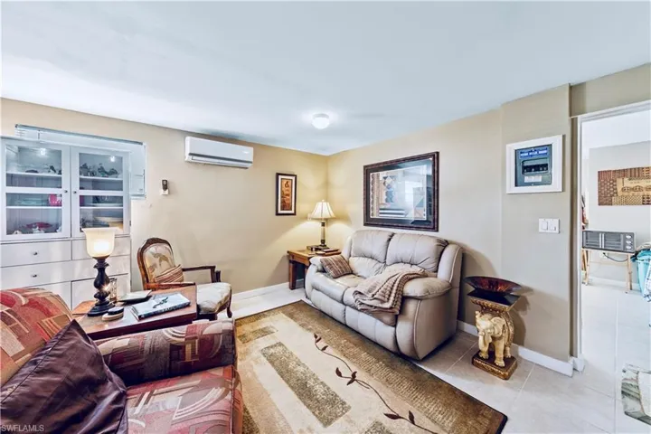 Living room with tile patterned floors, baseboards, and a wall mounted air conditioner