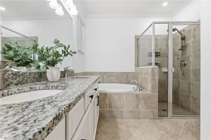 Full bathroom featuring a bath, a shower stall, crown molding, double vanity, and recessed lighting