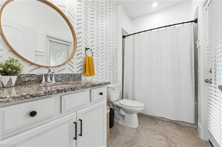 Full bathroom featuring vanity, shower / bath combo, and wallpapered walls