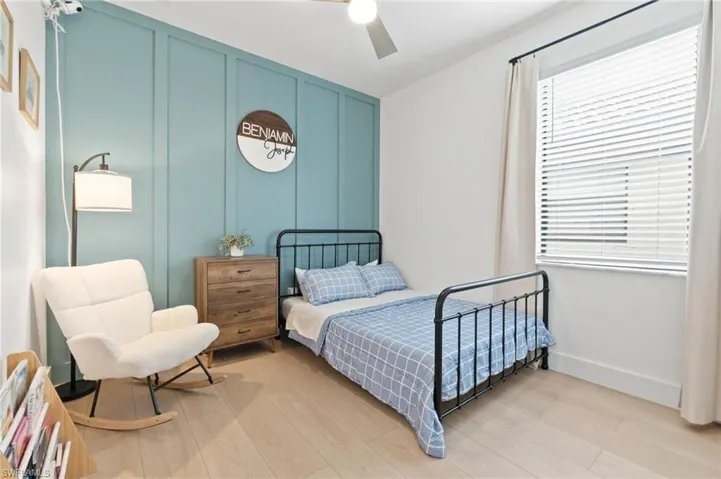 Bedroom featuring a decorative wall, wood finished floors, and ceiling fan