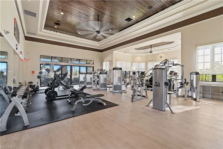 Workout area featuring ceiling fan, a high tray ceiling, and ornamental molding
