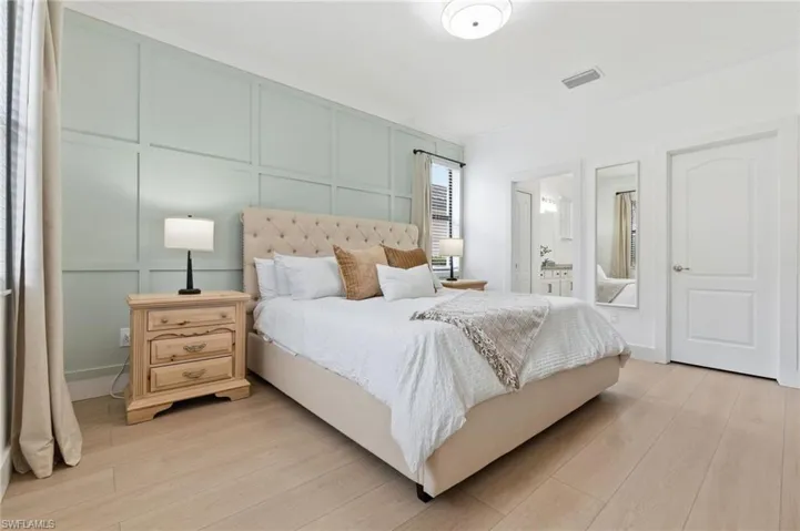 Bedroom with a decorative wall, light wood-style floors, and ensuite bathroom