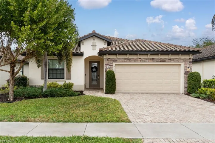 Mediterranean / spanish-style home with stone siding, stucco siding, an attached garage, and decorative driveway