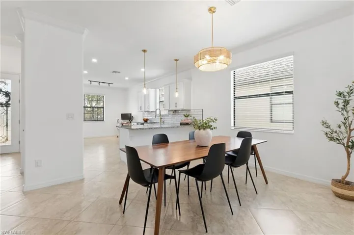 Dining space with ornamental molding, light tile patterned flooring, and recessed lighting