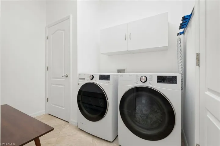 Laundry area featuring cabinet space, washer and clothes dryer, and light tile patterned floors