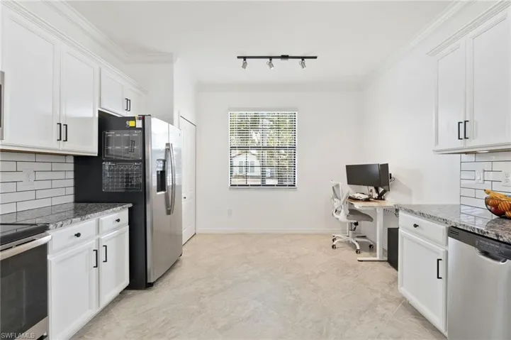 Kitchen with tasteful backsplash, stainless steel appliances, track lighting, dark stone countertops, and crown molding