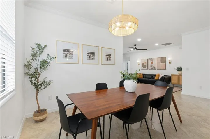 Dining area featuring ornamental molding, ceiling fan, a chandelier, and light tile patterned floors