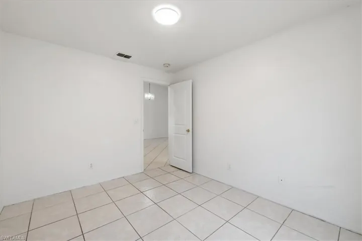 Room featuring light-toned tile flooring, white walls, and a flush-mount ceiling light