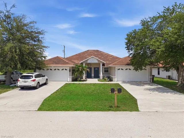 Duplex property featuring a neutral stucco exterior, brown tile roofing, and two distinct entrances with blue doors
