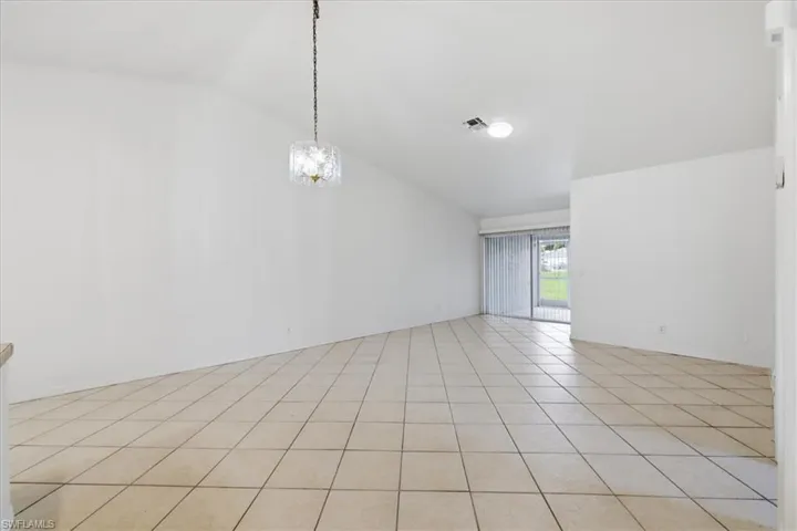 Spacious interior with vaulted ceilings, neutral tile flooring, and a sliding glass door providing outdoor access