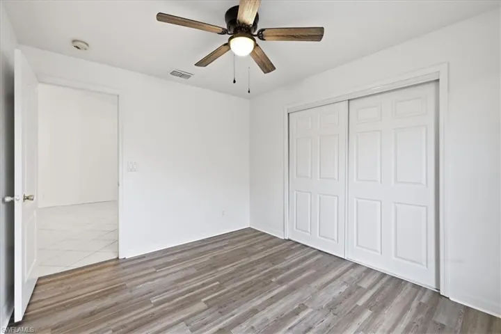 Room featuring wood-finish flooring and a ceiling fan with integrated lighting
