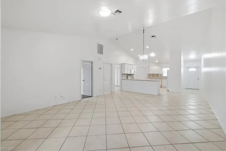 Open concept living area featuring vaulted ceilings, tile flooring, recessed lighting, and a chandelier