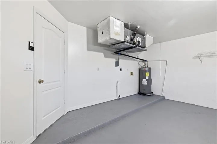Utility space featuring a water heater, overhead HVAC unit, and wire shelving