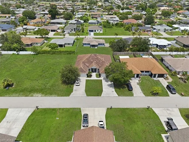 Expansive residential lot featuring a paved driveway, established trees, and ample green space
