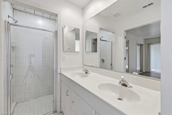 Bathroom featuring a dual vanity with integrated sinks, a white countertop, and white cabinetry