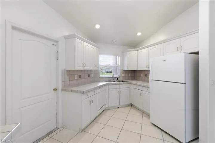 Kitchen featuring white cabinetry, tile countertops, tile backsplash, and recessed lighting