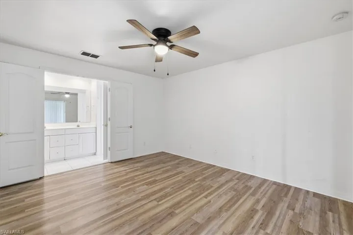 Bedroom featuring wood-finish flooring, a ceiling fan with integrated lighting, and white walls