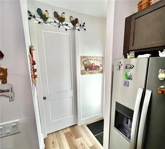 Kitchen with dark brown cabinetry, light wood-type flooring, and stainless steel fridge with ice dispenser