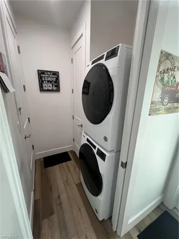 Clothes washing area featuring stacked washer / dryer and hardwood / wood-style floors