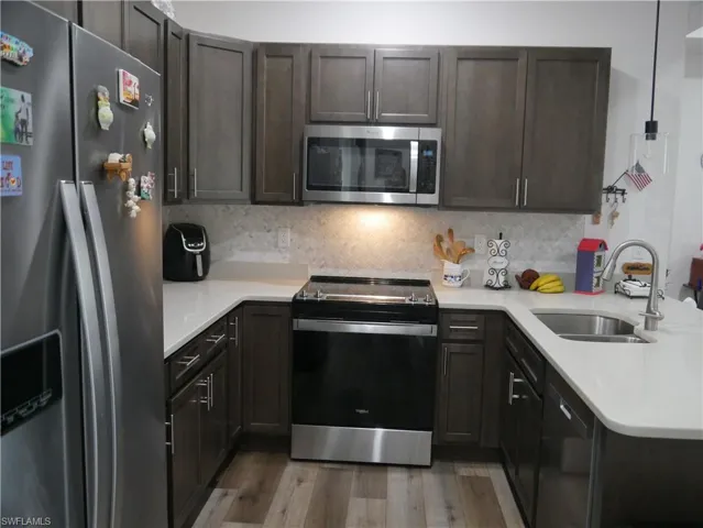 Kitchen with stainless steel appliances, hardwood / wood-style flooring, tasteful backsplash, sink, and pendant lighting