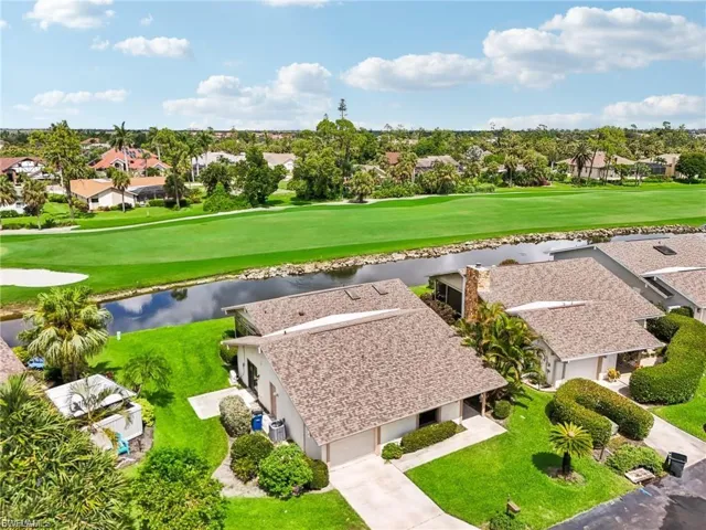 Aerial perspective of suburban area featuring a nearby body of water and a golf course