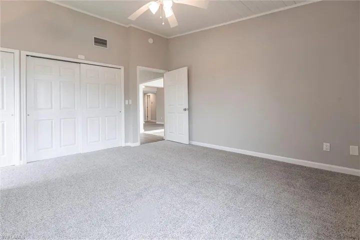 Unfurnished bedroom with ornamental molding, carpet, ceiling fan, and a closet