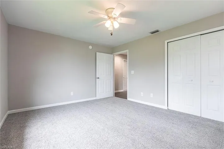 Unfurnished bedroom with a closet, carpet, and ceiling fan