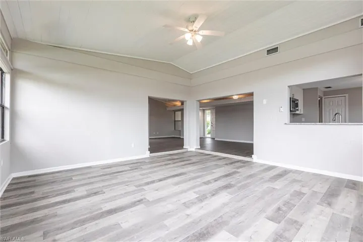 Empty room with vaulted ceiling, light wood-type flooring, and ceiling fan