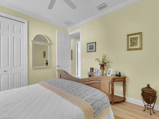Bedroom with wood finished floors, a closet, crown molding, and a ceiling fan