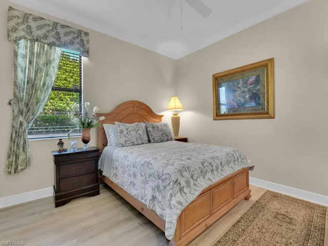 Bedroom featuring light wood-style flooring, ornamental molding, and ceiling fan